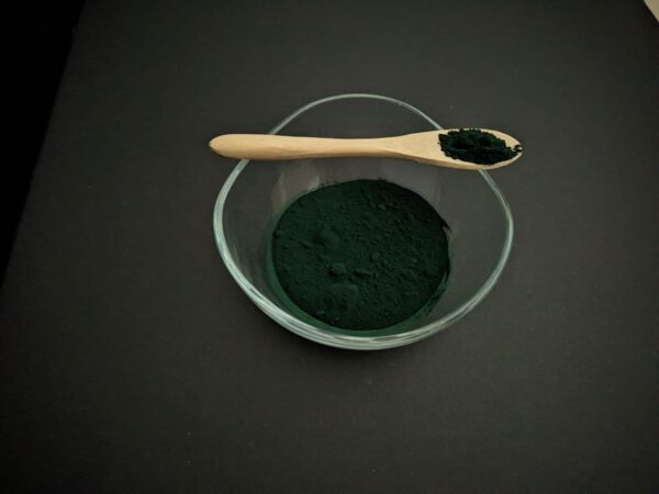 Spirulina-Pulver-in-einer-Glasschuessel-und-Holz-Loeffel